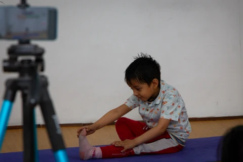 A small boy performs Janu Shirsasana